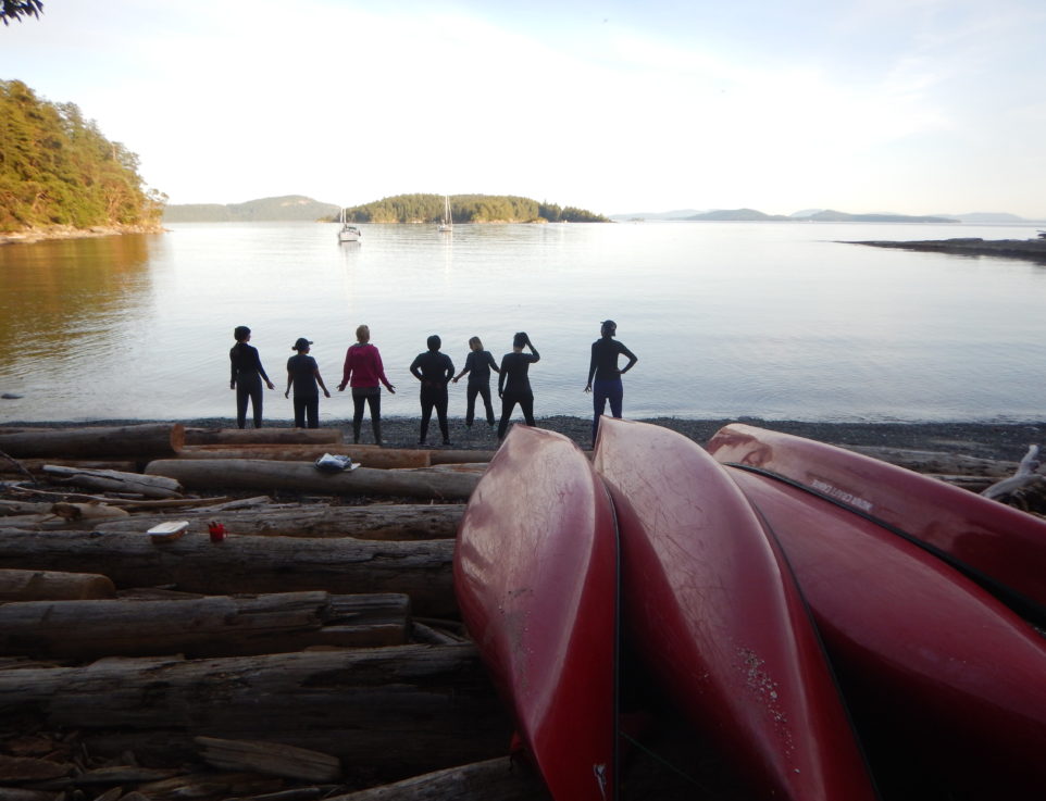 Silhouettes of line of people on shore of a lake