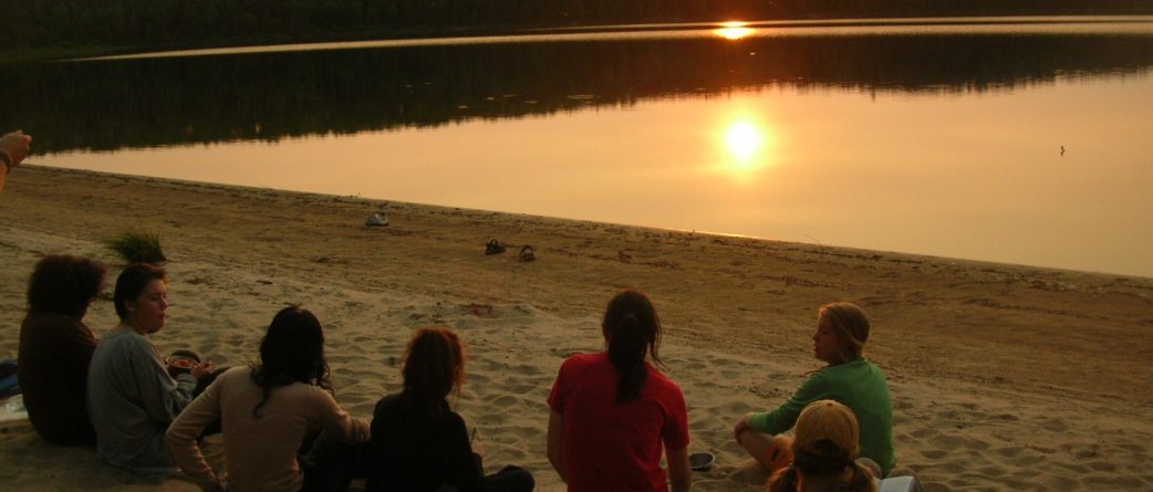 teens sitting on a beach at sunset