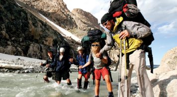 group of hikers crossing a river