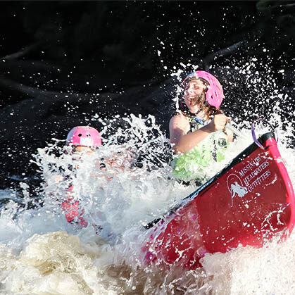 Image of water splashing on two teen sitting in a canoe
