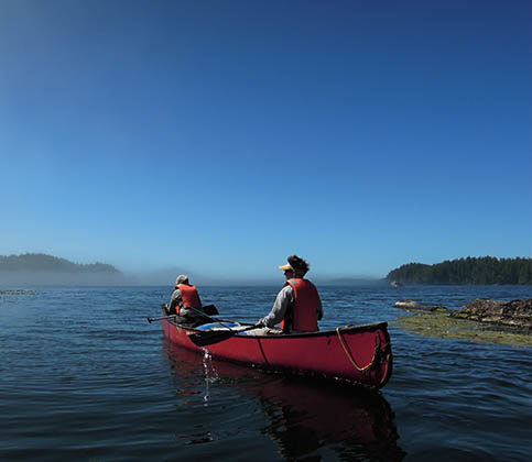 Image of two people canoeing in the vast blue ocean