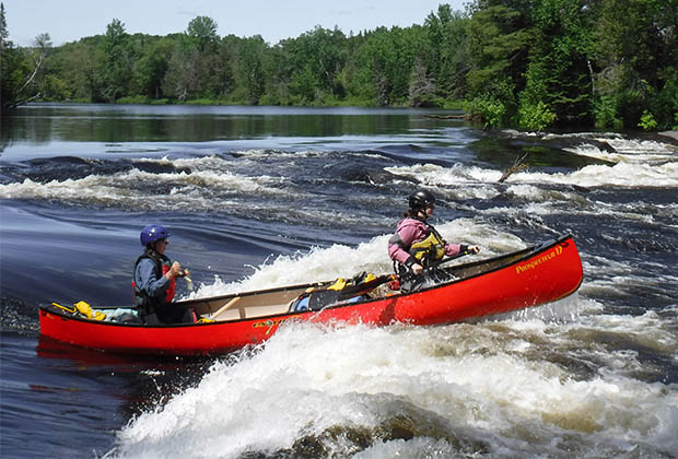 Image of two people paddling a red canoe