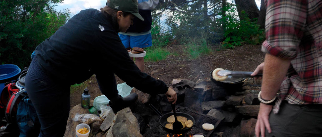 Image of people cooking on campfire in the forest