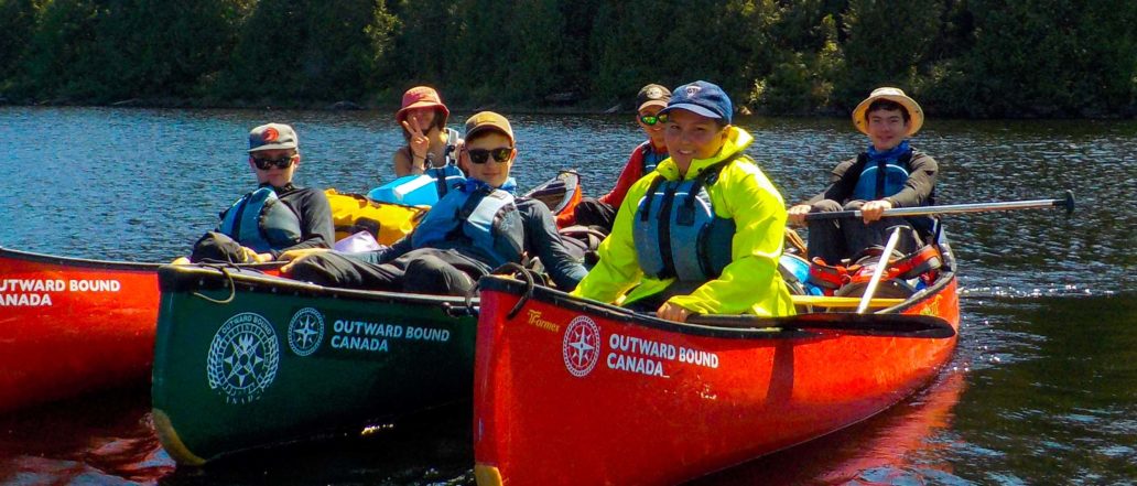 Image of a group of youth in canoes on a lake
