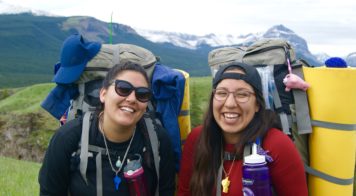 Two people smiling with backpacks on