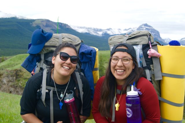Two people smiling with backpacks on