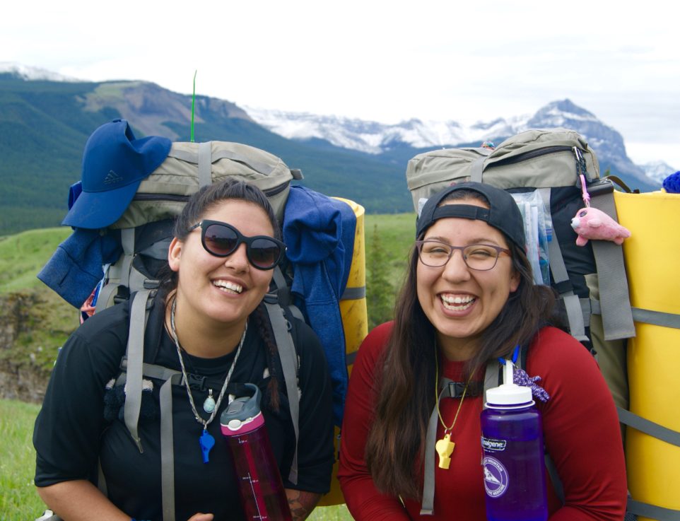 Two people smiling with backpacks on
