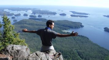 person sitting on rock overlooking ocean
