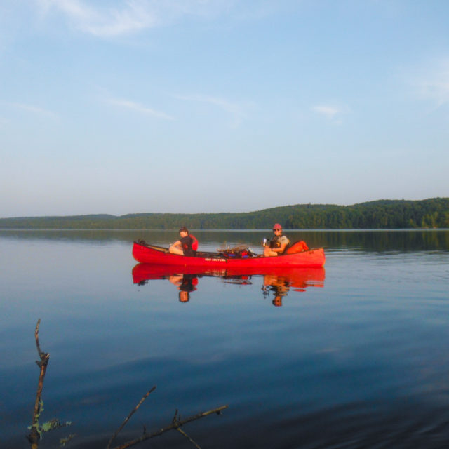 Image of 2 people in a canoe on a still lake