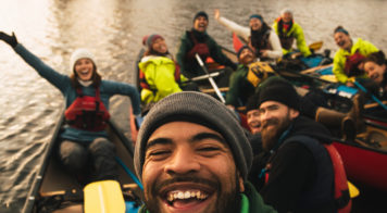 Image of a group of people in canoes smiling with their arms raised