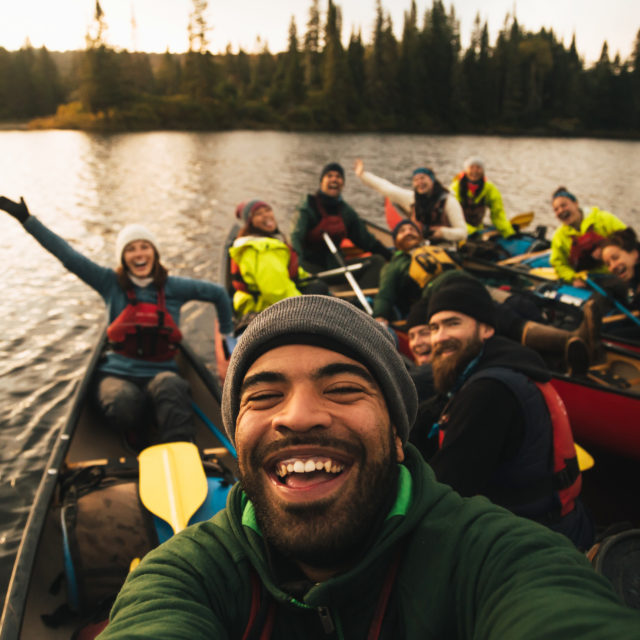 Image of a group of people in canoes smiling with their arms raised