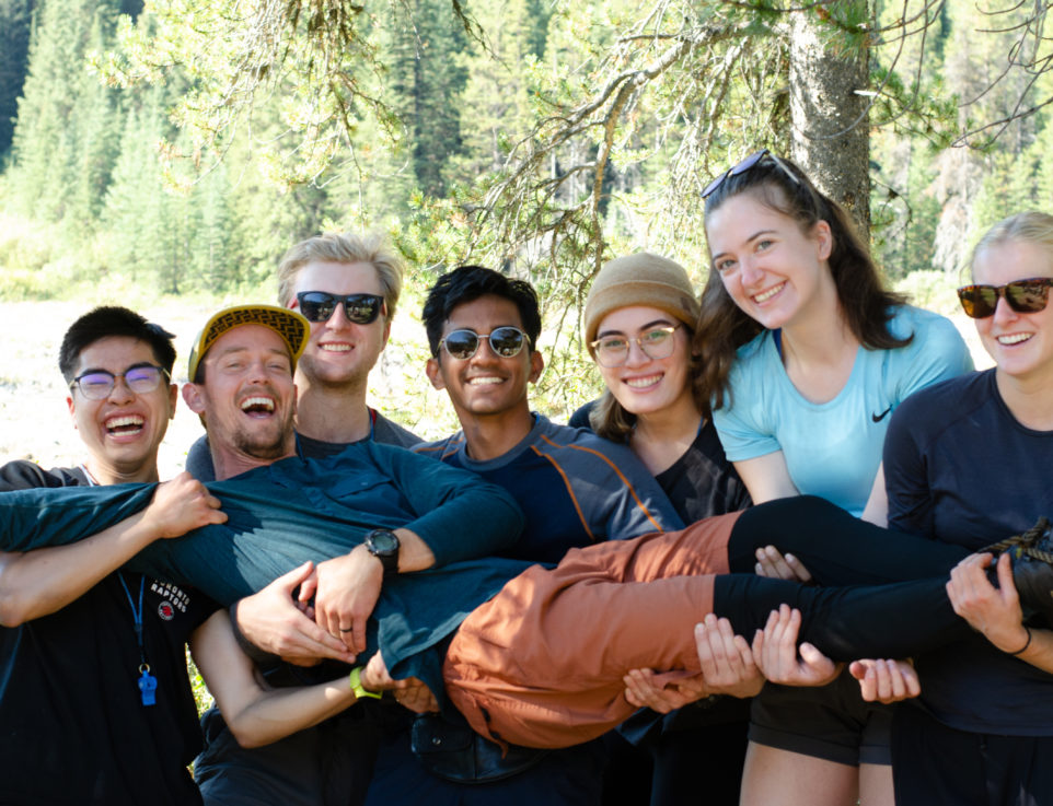 A group of young adults holding one of their friends