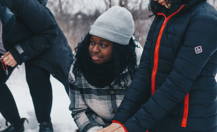 two teens making a fire in the snow