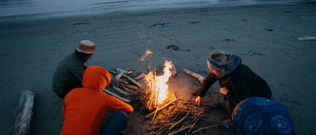 Image of 3 people around a campfire on a beach