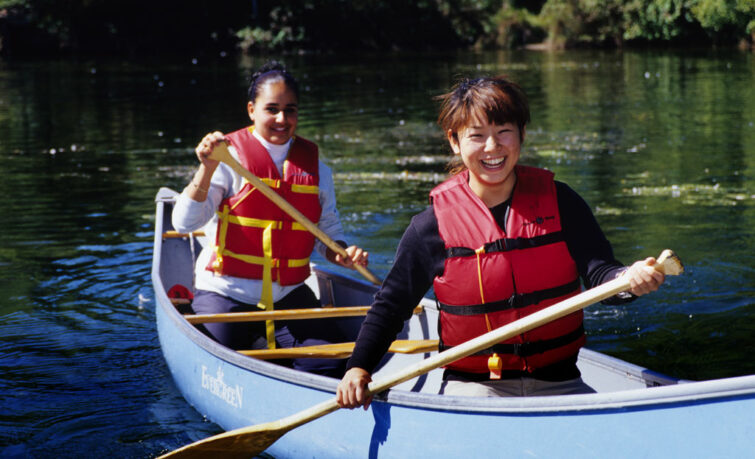 two teens canoeing on flat water