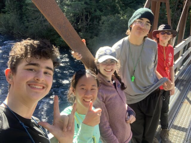 teens smiling and posing for a selfie on a bridge