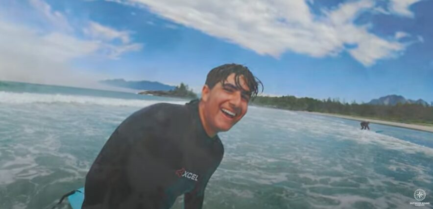 boy in ocean on surfboard smiling pov