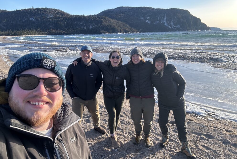 teens taking a selfie smiling on beach with mountain background