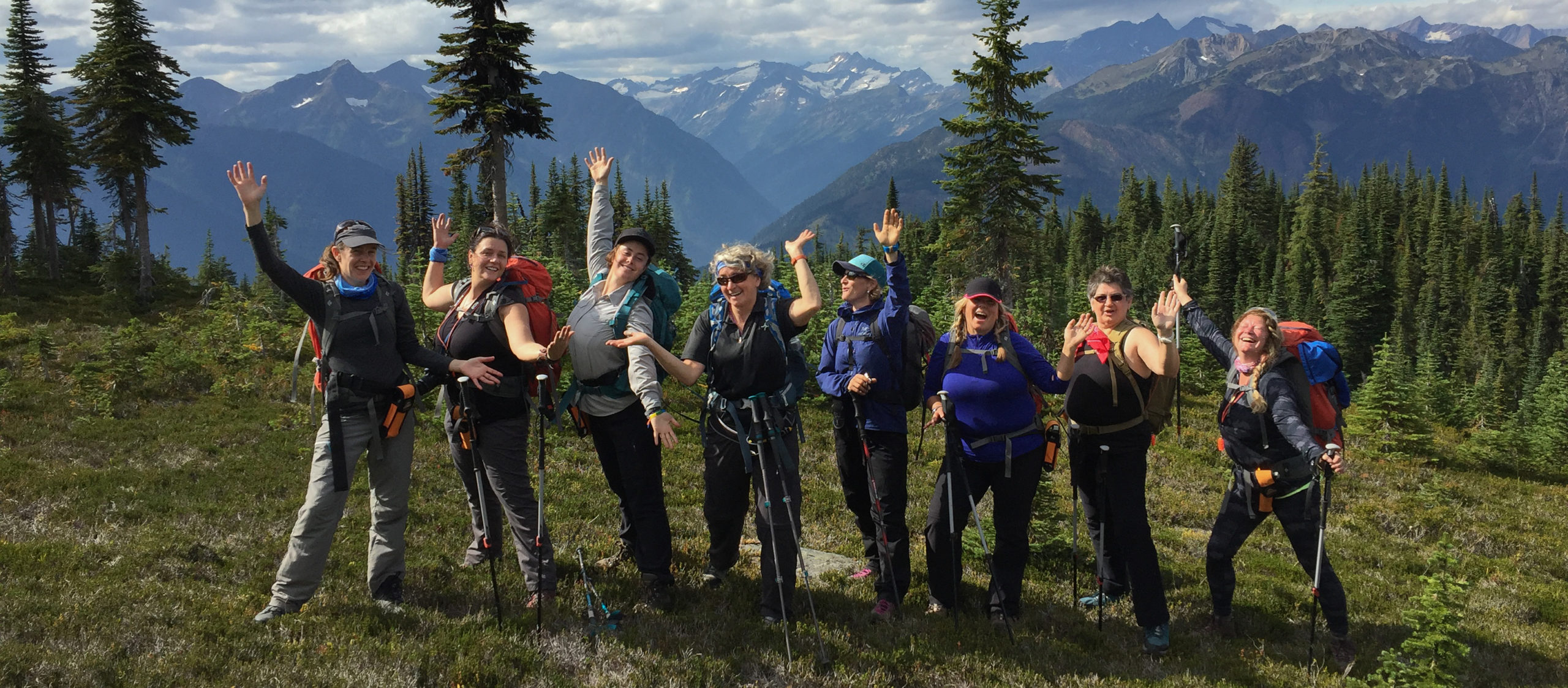 Eight people standing in a line with their arms up