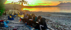 Image of a group sitting on a wooden log and reading books