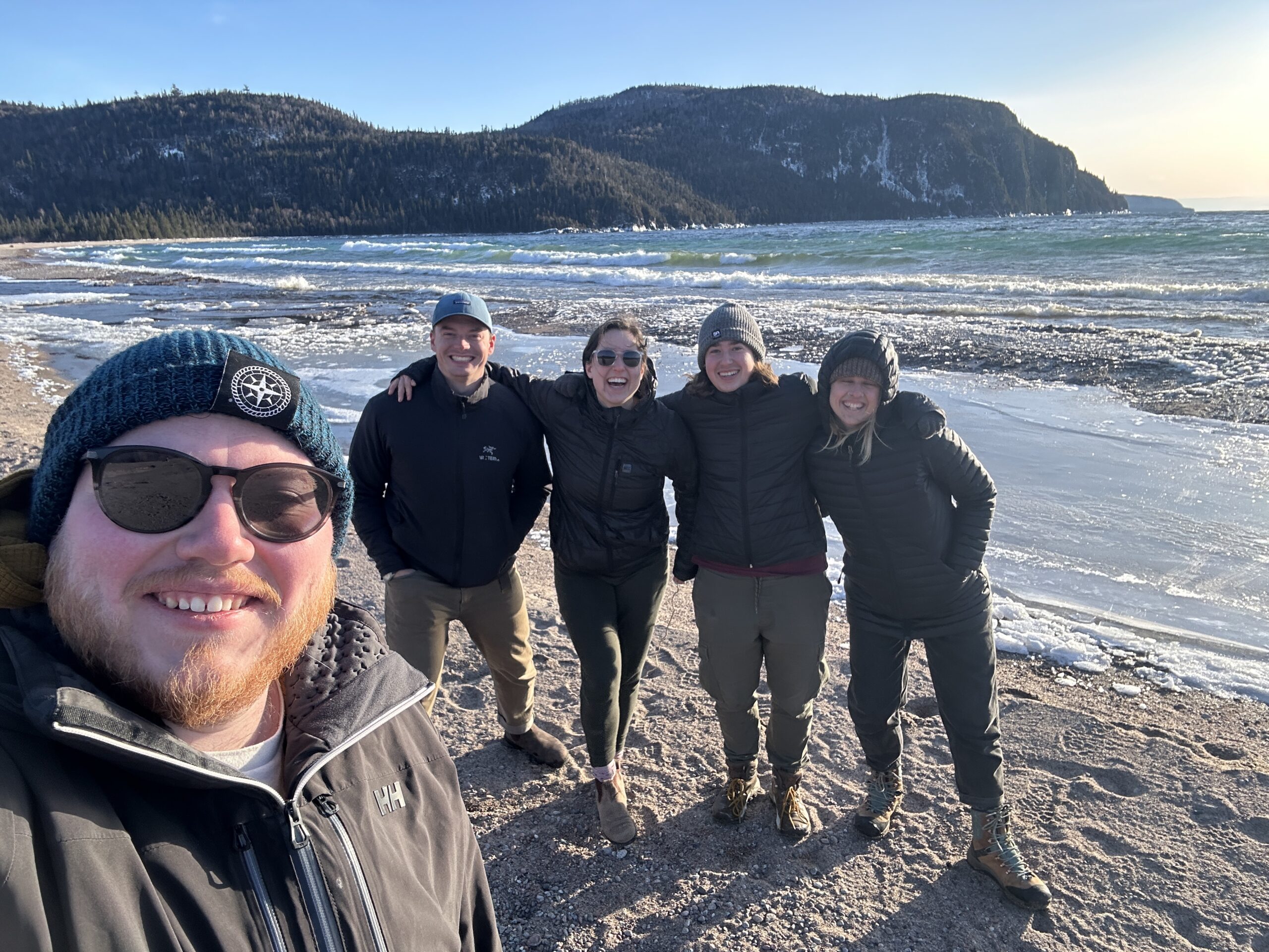 teens taking a selfie smiling on beach with mountain background