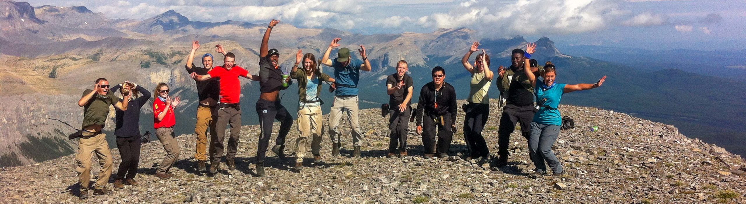 A group jumping in the air at the top of a mountain