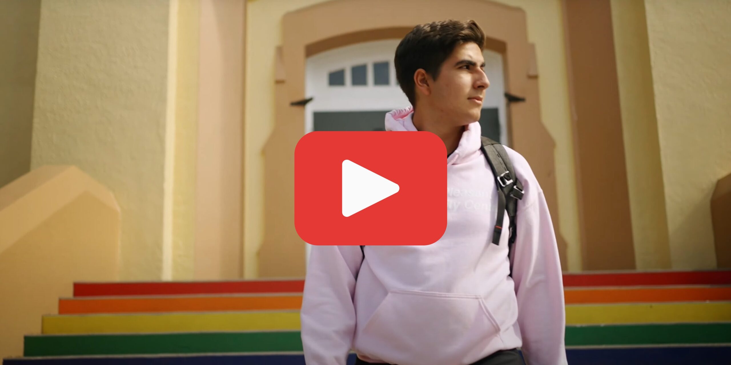 boy standing infront of school steps with play button overlay