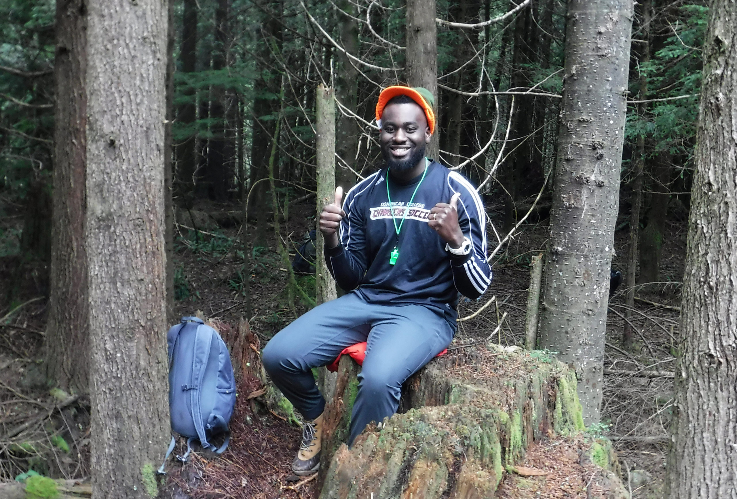man sitting on treestump with thumbs up