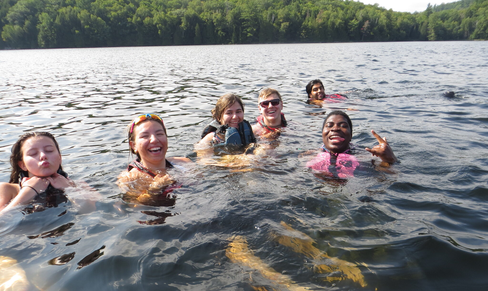 Group of five youth swimming in a lake in Algonquin Park