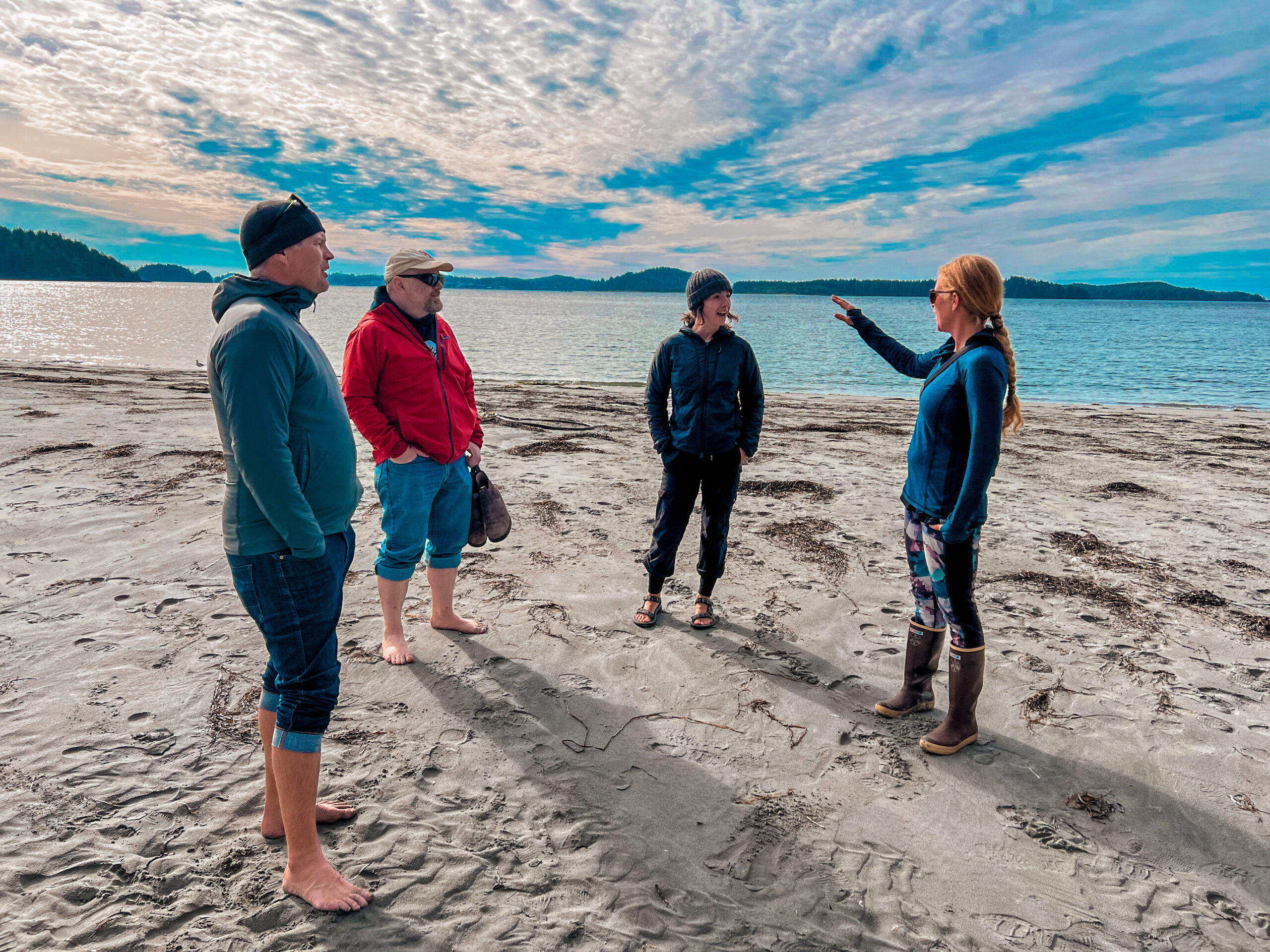 people standing on a beach listening to instructor with ocean background