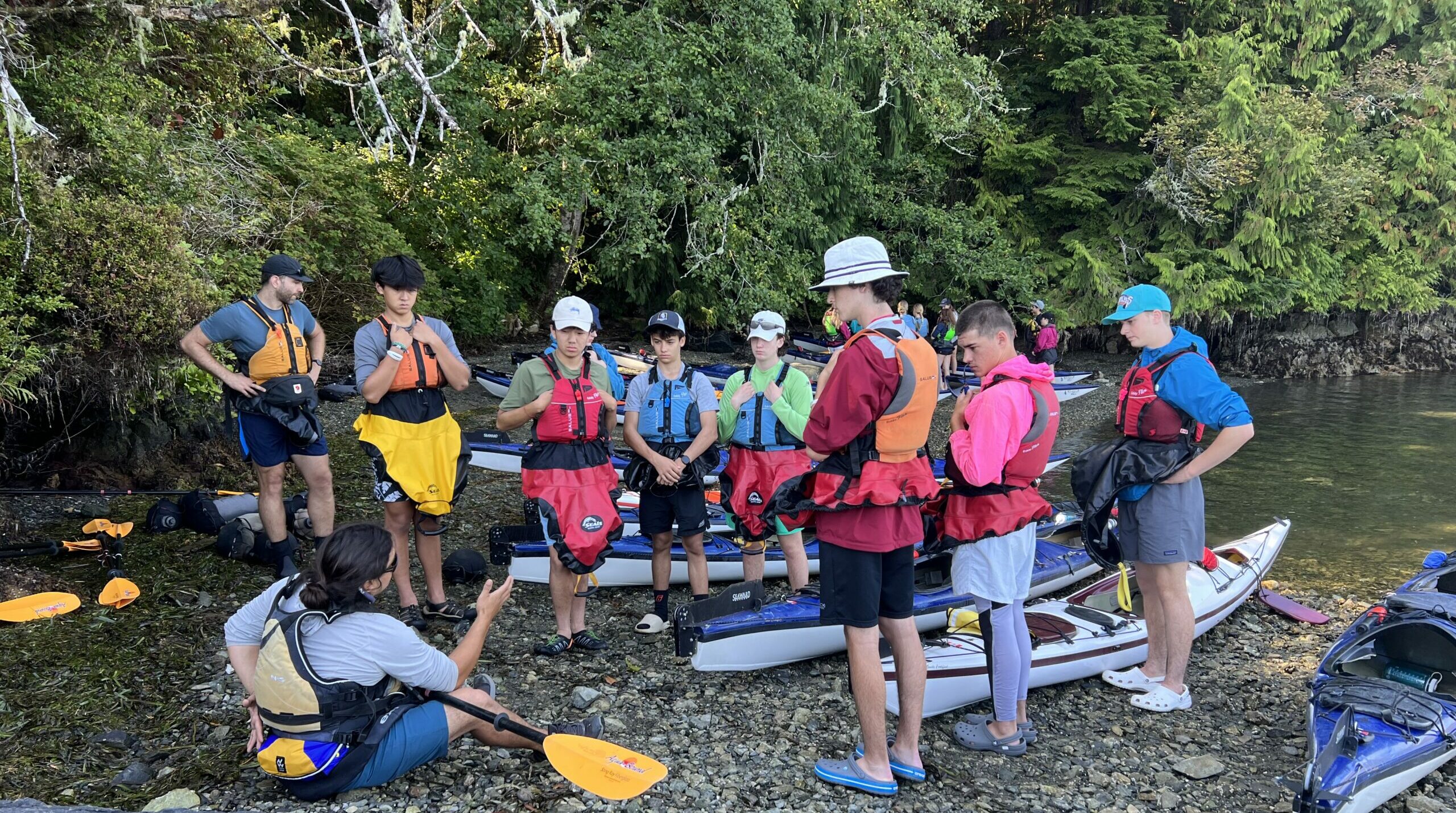 people in lifejackets sitting on a beach