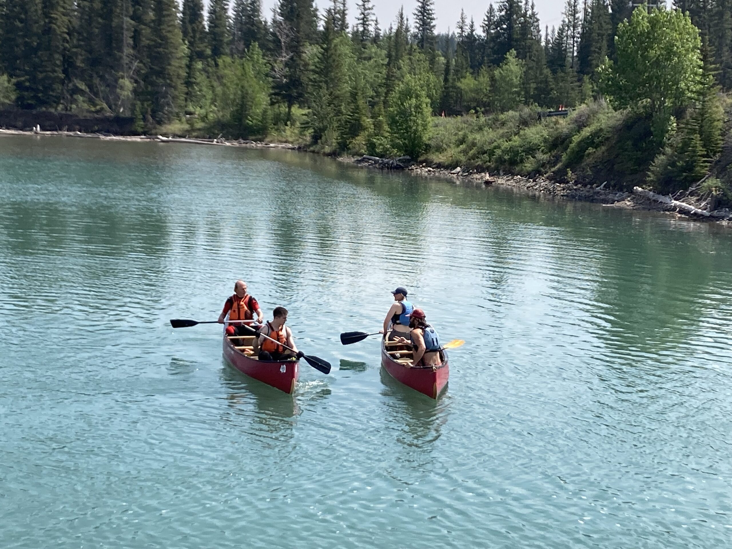 three red canoes aerial shot on a lake in the Rocky Mountains