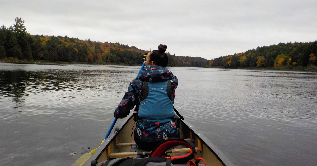 Person paddling in a lifejacket in the front of a canoe