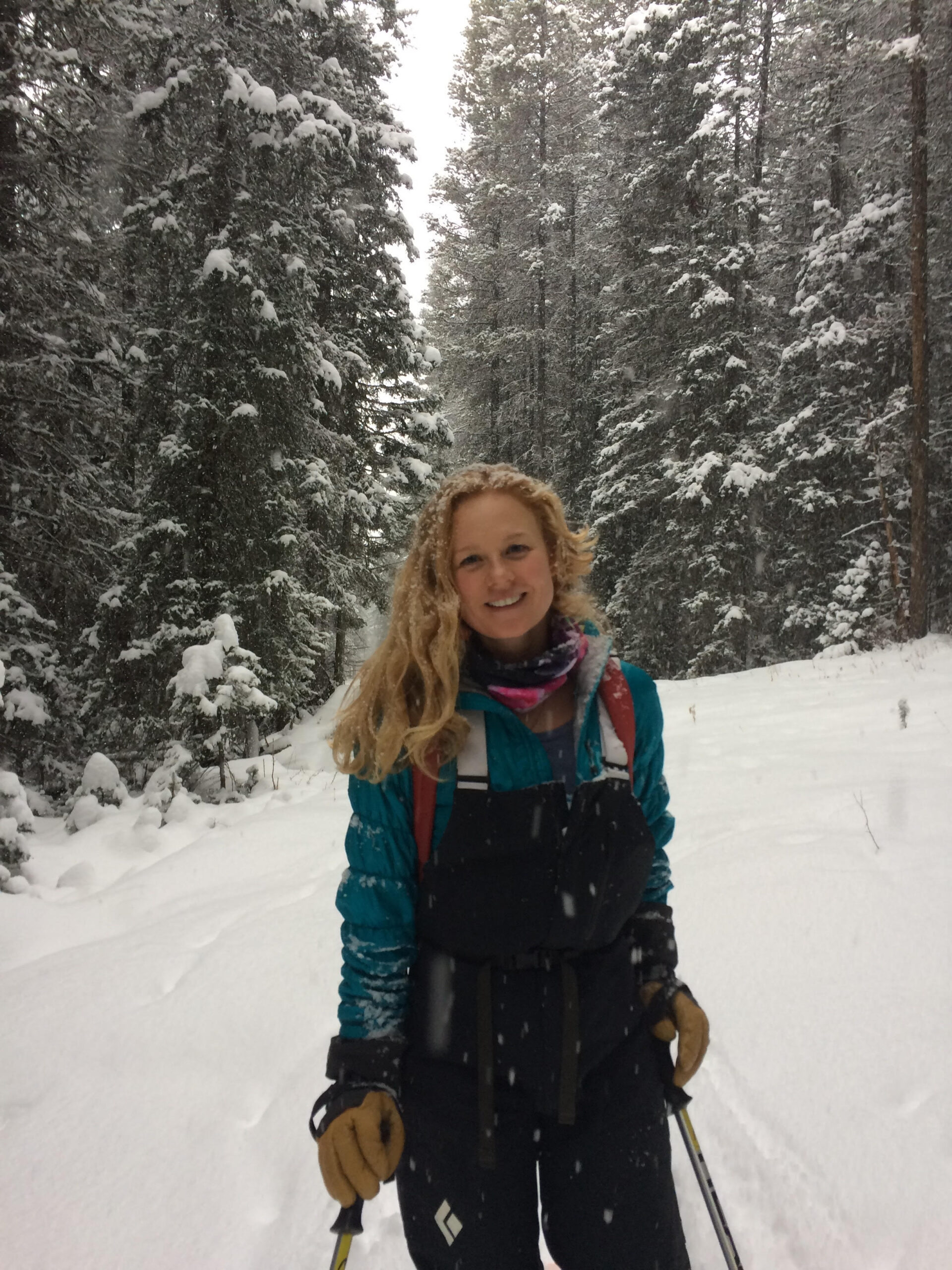Woman smiling standing in a snow covered forest
