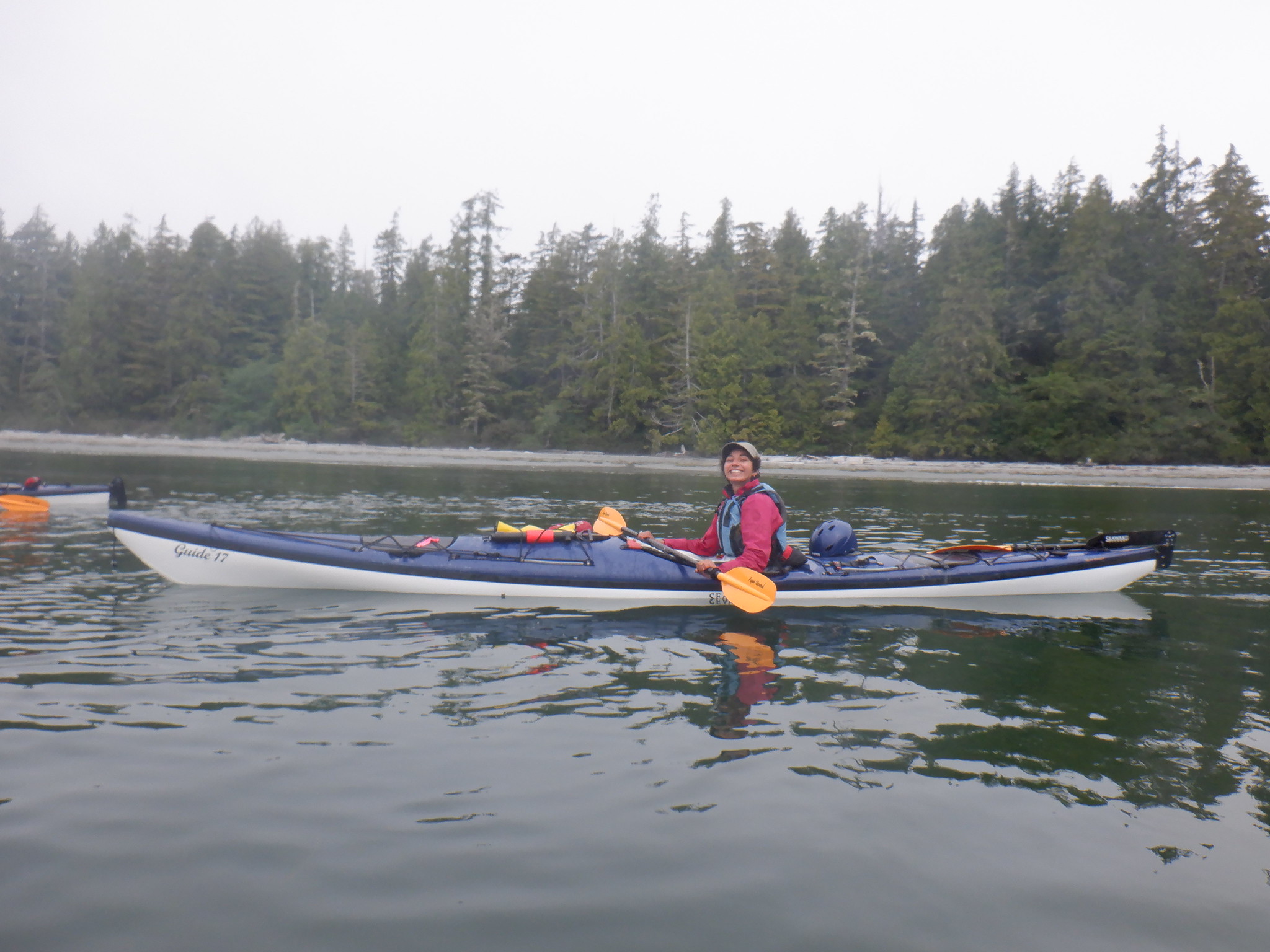 Young BIPOC female outdoor guide Shams Ben Temessek paddles a kayak in a lake