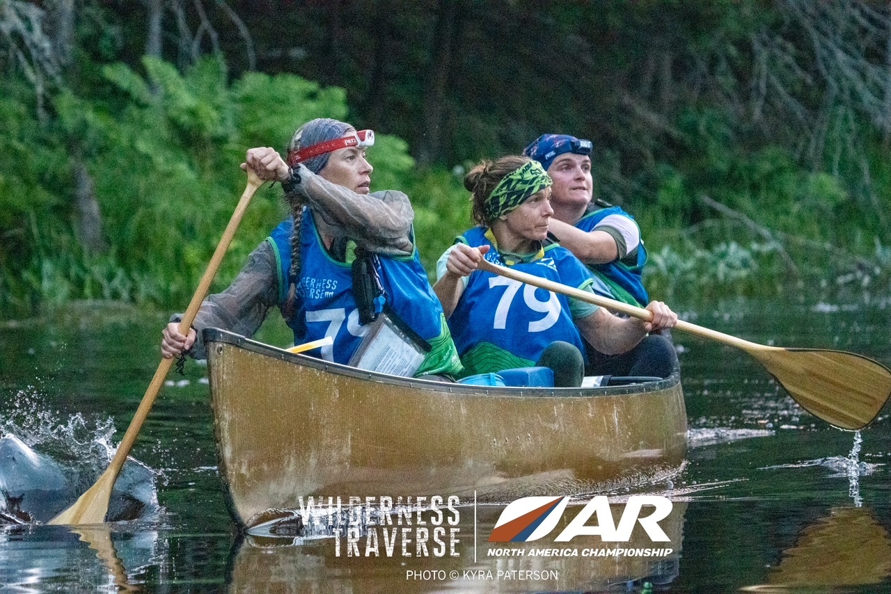 Three members of The Breakfast Club paddling a canoe during Wilderness Traverse.